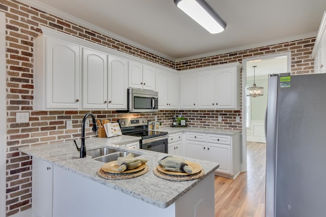 kitchen featuring a peninsula, brick wall, stainless steel appliances, and a sink