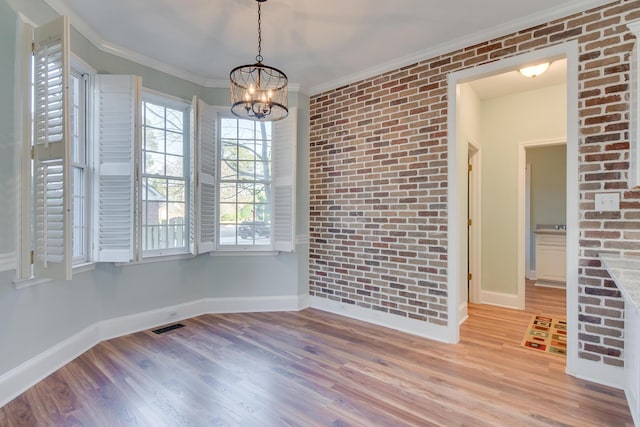 empty room with baseboards, brick wall, ornamental molding, and wood finished floors