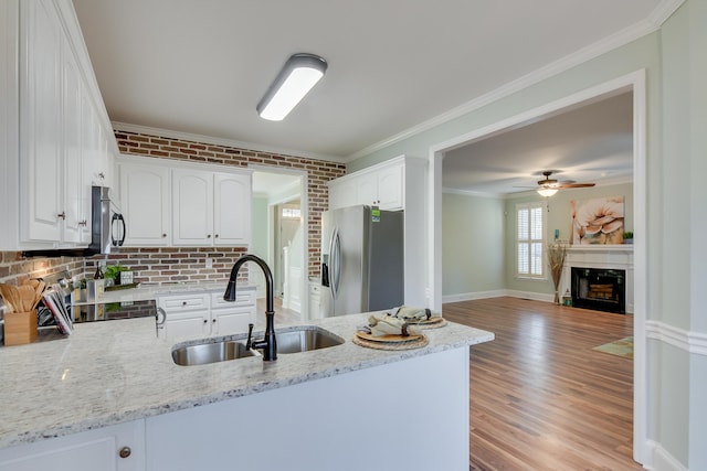 kitchen with a peninsula, stainless steel appliances, crown molding, a fireplace, and a sink