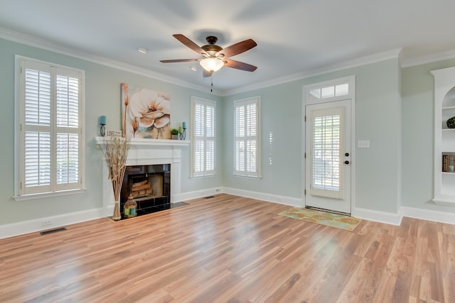 unfurnished living room with ornamental molding, a fireplace with flush hearth, visible vents, and a healthy amount of sunlight