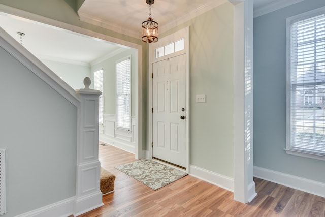 foyer entrance featuring stairway, light wood-style flooring, and ornamental molding