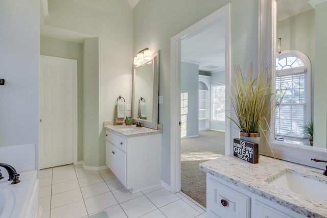 bathroom with baseboards, a sink, tile patterned flooring, a bathtub, and two vanities