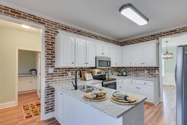 kitchen featuring brick wall, appliances with stainless steel finishes, white cabinets, and a sink