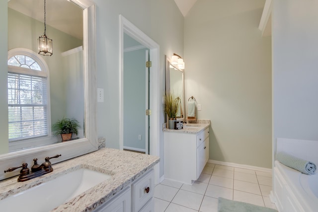 bathroom featuring tile patterned flooring, two vanities, a sink, baseboards, and a bath