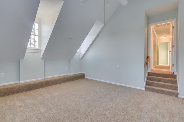 bonus room featuring ceiling fan, carpet flooring, visible vents, baseboards, and lofted ceiling with skylight