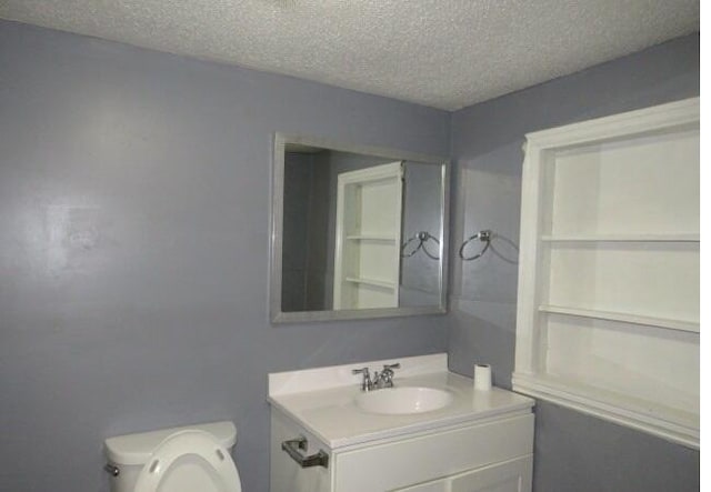 bathroom featuring vanity, a textured ceiling, and toilet