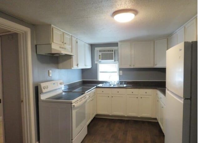 kitchen with white appliances, dark wood-type flooring, sink, a wall mounted AC, and white cabinetry