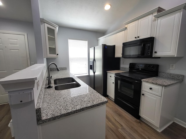 kitchen featuring dark wood-style floors, black appliances, a peninsula, and a sink