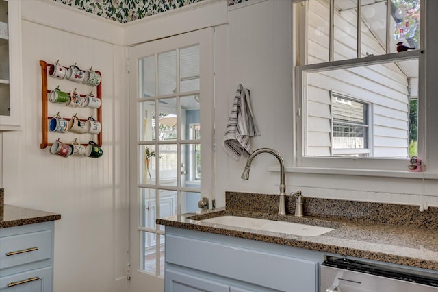 1958 Mcdowell St, Augusta, GA 30904 - kitchen with stainless steel dishwasher, a sink, plenty of natural light, and dark stone counters