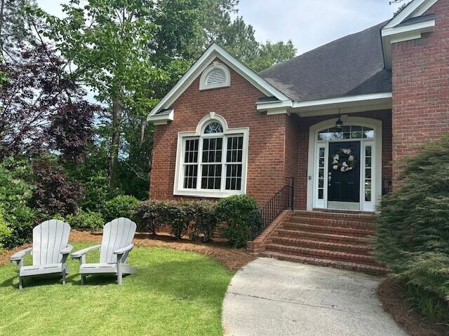 3218 Ramsgate Rd, Augusta, GA 30909 - view of exterior entry with a yard, brick siding, and roof with shingles