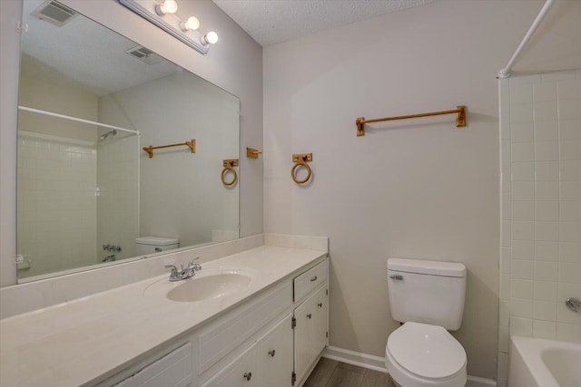 full bathroom with hardwood / wood-style floors, a textured ceiling, toilet, vanity, and tiled shower / bath