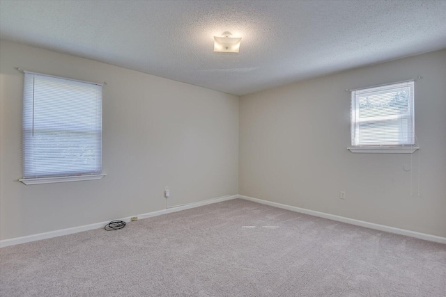 spare room with light colored carpet and a textured ceiling