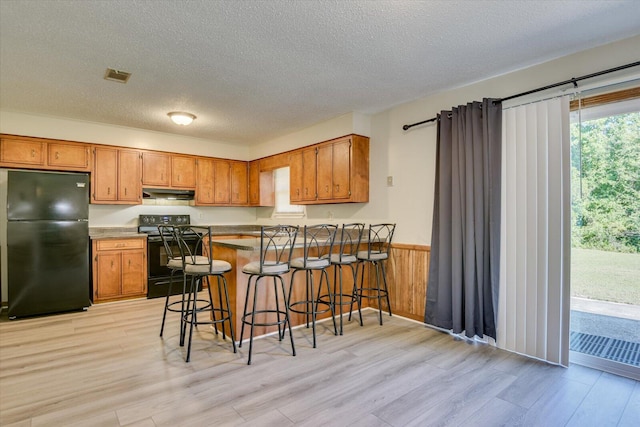 kitchen with kitchen peninsula, a healthy amount of sunlight, a breakfast bar, and black appliances