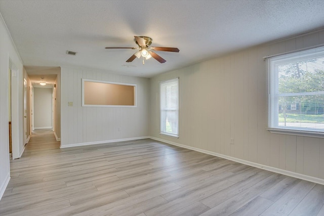 unfurnished room featuring ceiling fan, a healthy amount of sunlight, a textured ceiling, and light wood-type flooring