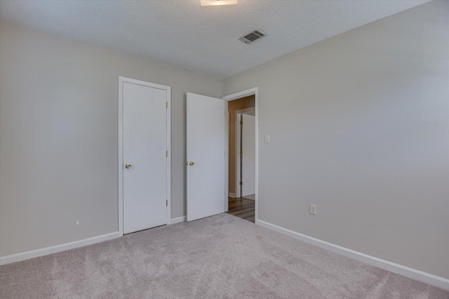 unfurnished bedroom with light carpet and a textured ceiling