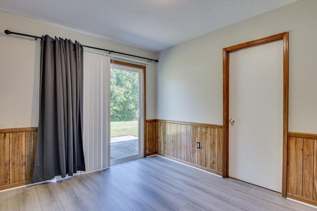 empty room with a textured ceiling and light hardwood / wood-style flooring