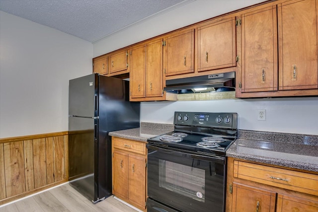 kitchen with a textured ceiling, light hardwood / wood-style floors, wooden walls, and black appliances