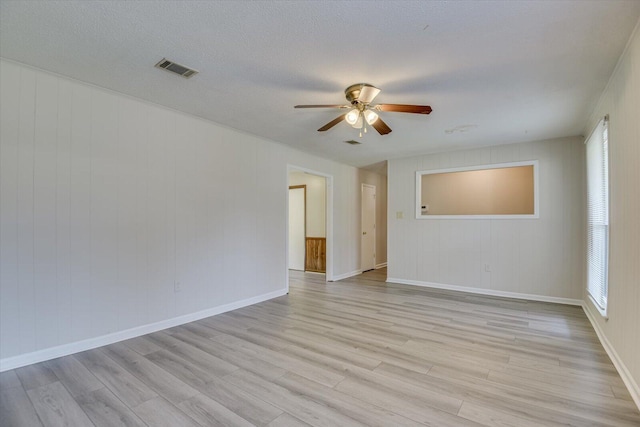 empty room with a textured ceiling, light wood-type flooring, and ceiling fan