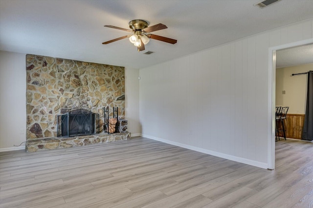 unfurnished living room featuring a fireplace, a textured ceiling, light hardwood / wood-style floors, and ceiling fan