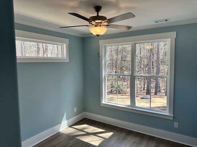 empty room featuring visible vents, baseboards, dark wood finished floors, and ornamental molding