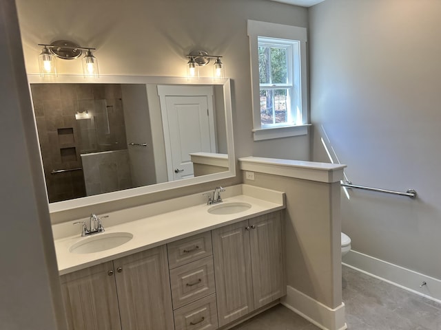 full bathroom with tiled shower, toilet, baseboards, and a sink