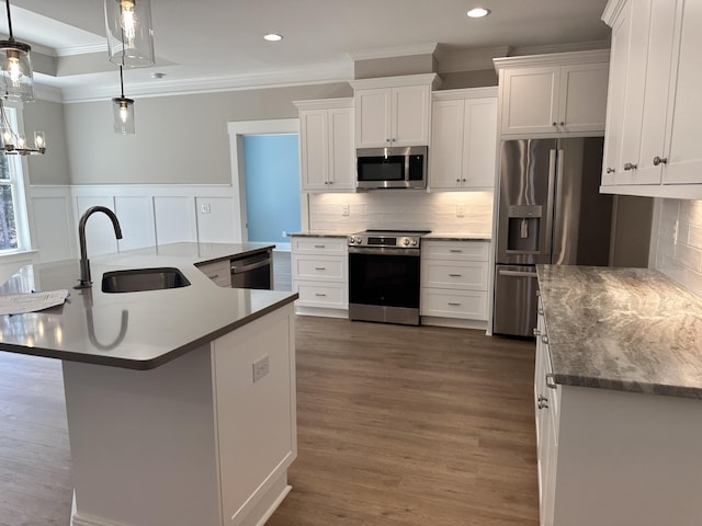 kitchen featuring a sink, tasteful backsplash, stainless steel appliances, wainscoting, and crown molding