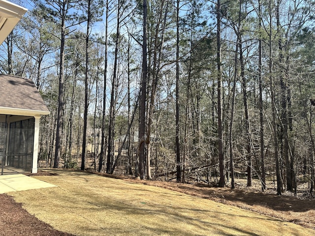 view of yard featuring a view of trees and a sunroom