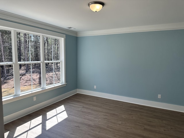 unfurnished room with visible vents, dark wood-type flooring, baseboards, and ornamental molding