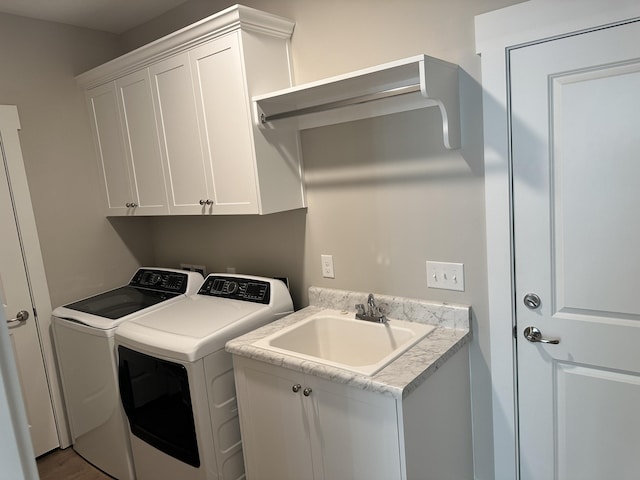 laundry room with cabinet space, independent washer and dryer, and a sink