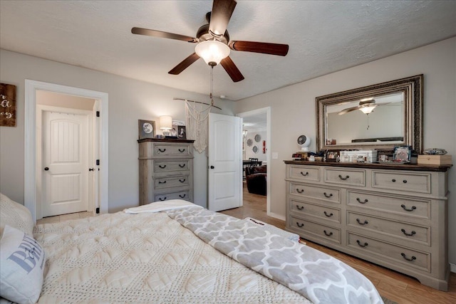 bedroom featuring a textured ceiling, light wood-style flooring, and a ceiling fan