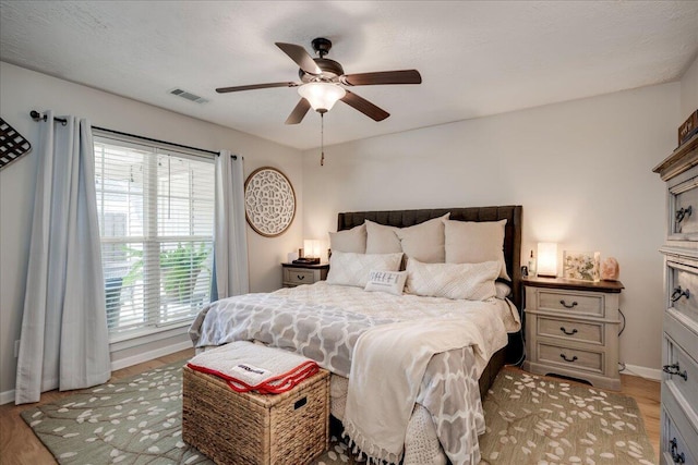 bedroom with baseboards, a ceiling fan, visible vents, and light wood-style floors