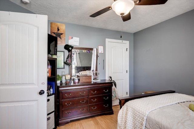 bedroom featuring light wood-type flooring, ceiling fan, and a textured ceiling