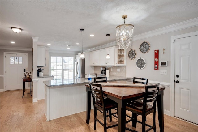 dining area featuring light wood-style floors, crown molding, a textured ceiling, and an inviting chandelier