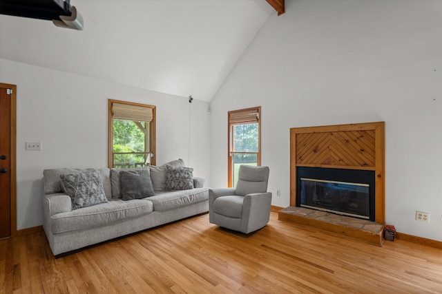 living room featuring high vaulted ceiling, a glass covered fireplace, wood finished floors, and beamed ceiling