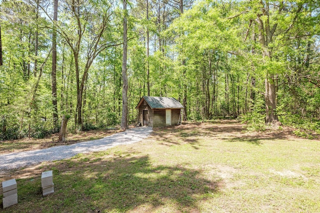 view of yard with an outbuilding, a wooded view, and a shed