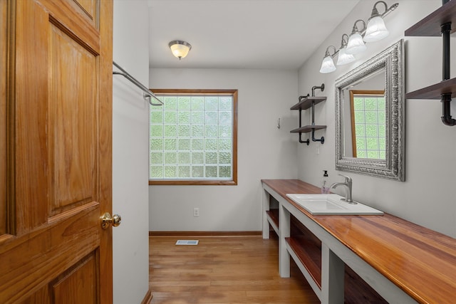 bathroom featuring baseboards, vanity, wood finished floors, and visible vents