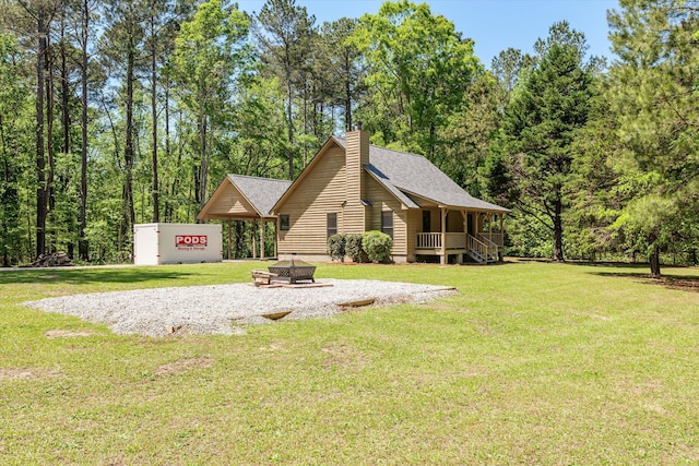 exterior space with a fire pit, roof with shingles, a chimney, and a lawn