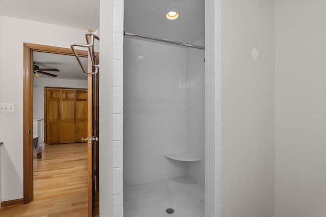 bathroom with a ceiling fan, wood finished floors, and tiled shower