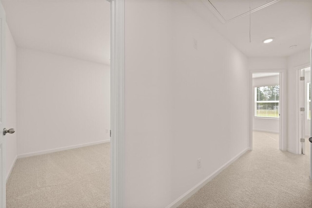 hallway featuring carpet flooring, attic access, and baseboards