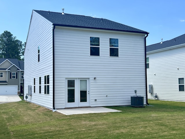 rear view of house featuring a patio area, a yard, central AC unit, and a shingled roof