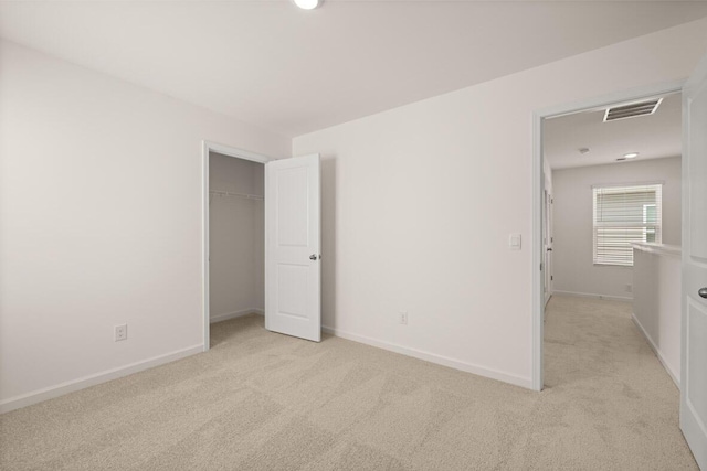 unfurnished bedroom featuring baseboards, light carpet, a closet, and visible vents