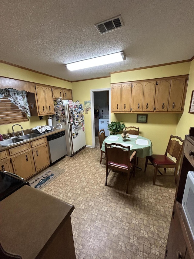 kitchen with stainless steel appliances, a sink, brown cabinets, ornamental molding, and washer / clothes dryer