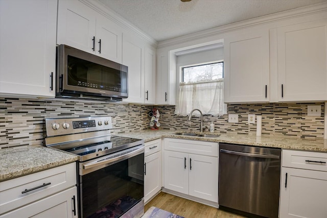 kitchen featuring white cabinetry, stainless steel appliances, sink, light stone counters, and a textured ceiling