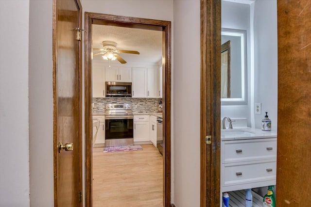 corridor featuring sink, a textured ceiling, and light hardwood / wood-style flooring