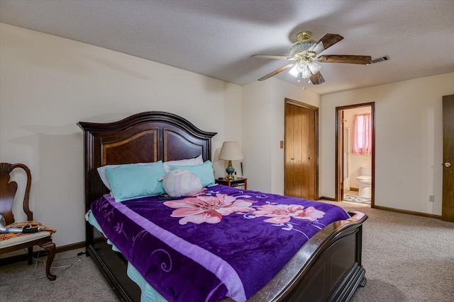 carpeted bedroom with a textured ceiling, connected bathroom, and ceiling fan