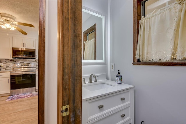 bathroom with hardwood / wood-style flooring, vanity, tasteful backsplash, and ceiling fan