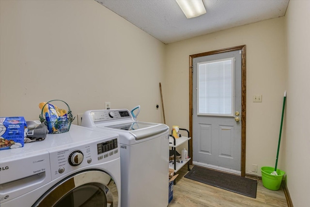 laundry area featuring a textured ceiling, washing machine and clothes dryer, and light hardwood / wood-style floors