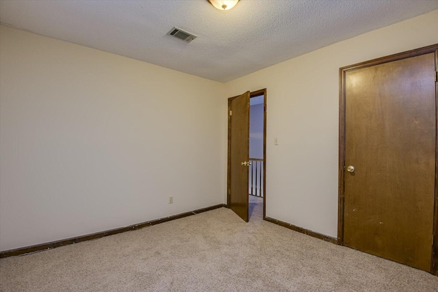 unfurnished bedroom featuring a textured ceiling and light carpet