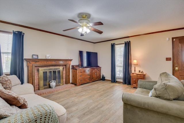 living room with light hardwood / wood-style floors, a wealth of natural light, crown molding, and a fireplace