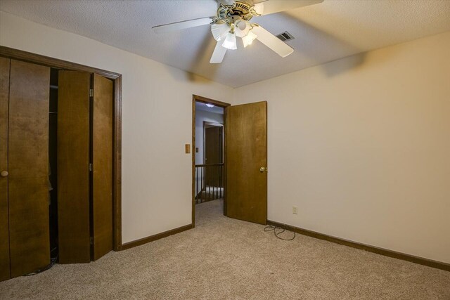 unfurnished bedroom with a textured ceiling, light carpet, ceiling fan, and a closet